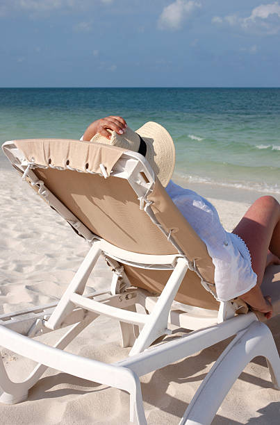 istock Woman sitting on deck chair at white sand beach. 184944809