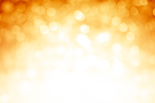 Blurred gold sparkles, defocused christmas lights. Bright bottom and middle, dark corners at the top.