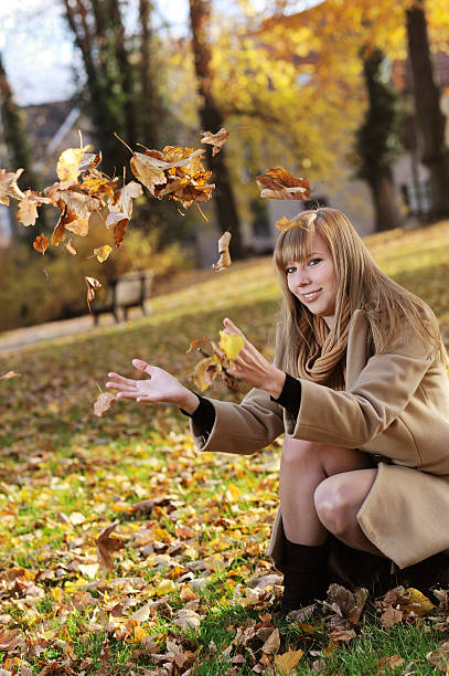 istock Young blond Woman playing with fall leaves 184945341