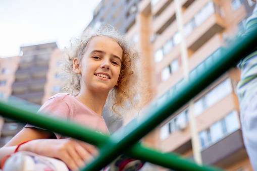 A charming teenage girl climbs the steps of an alpine staircase on a playground for children's games on a warm summer afternoon.