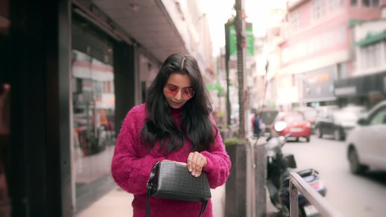 Pedestrian woman checks her purse while doing window shopping.