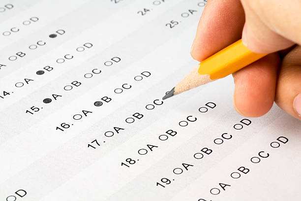 Pencil held over a multiple choice exam Hand completing a multiple choice exam.  The answer form was created by me and is not copyrighted. personality test stock pictures, royalty-free photos & images