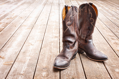 cowboy hat, boots and gun on a wooden floor