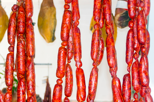 Chorizos hanging, cured ham, butcher sale in a market stall. Galicia, Spain.  Traditional food for cocido. Curing delicious spanish smoked chorizos