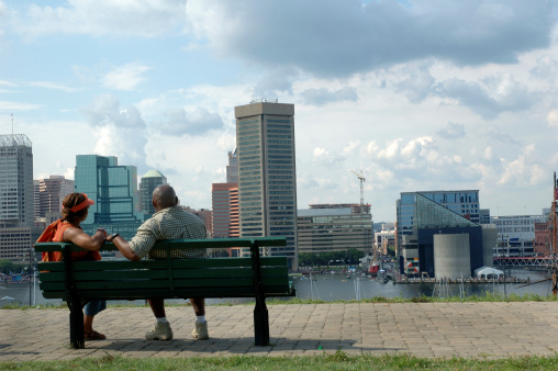 Middle-aged African-American couple look at the Baltimore harbor from the top of Federal Hill. The World Trade Center and National Aquarium can be seen on other side of harbor.
