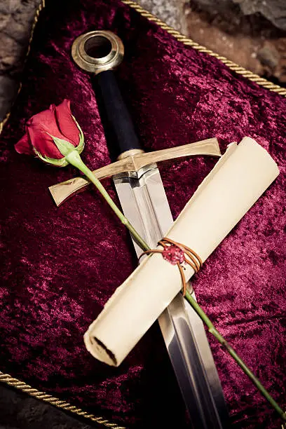 "Excalibur on a red velvet cushion with red rose and paper roll as symbol of will power,love and compromise for novel concepts,selective focus, creative dramatic color retouching to underline the ancient medieval time,vignetting and possible noisesee more:"