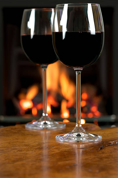 istock Two glasses of red wine on table with roaring fire 184949103