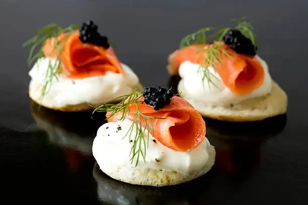Three smoked salmon blinis with caviar and a sprig of fresh dill.