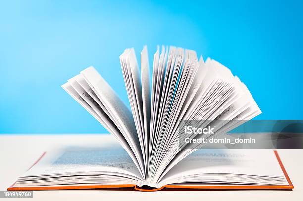 Open Book Paging Through Pages Lying On Table Blue Background Stock Photo - Download Image Now