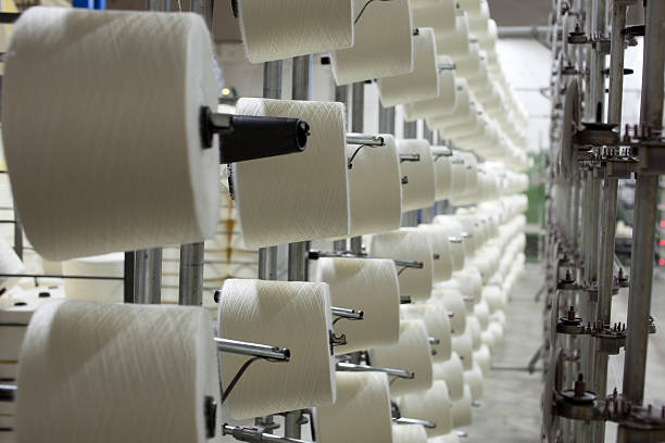 Rose of spools of string in a textile plant  Spinning machines making thread in Textile Spinning unit. ** Machine are operational some motion blur visible. cotton mill stock pictures, royalty-free photos & images