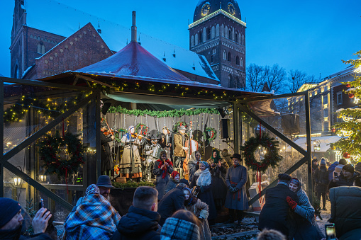Riga, Latvia - December 10, 2023: People at Christmas market in the Dome square in the center of old Riga. The ensemble of folk songs performs