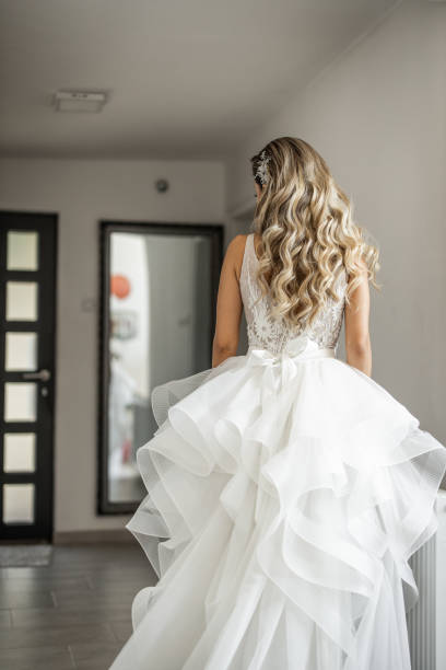istock Back view of bride standing in apartment and looking herself at mirror 1849530821