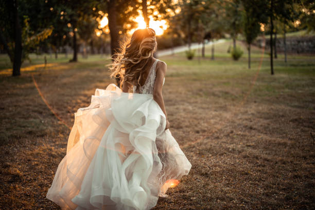 istock Back view of bride while running on lawn in park during sunset 1849530887