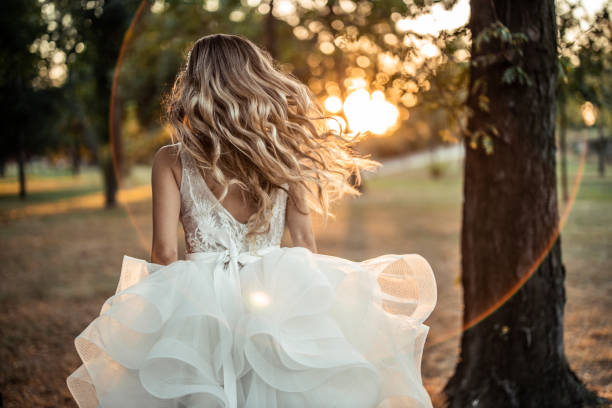istock Back view of bride while running on lawn in park during sunset 1849530888