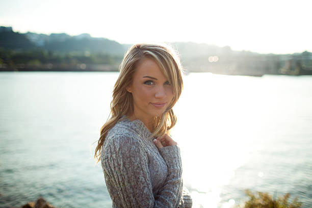 Young blonde woman standing by the river smiling.  Shallow depth of field.  Portland, OR