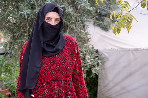 Portrait for woman wearing traditional clothes in refugee camp behinde olive tree