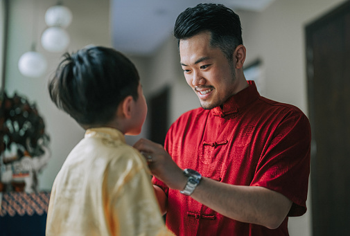 Chinese New Year father buttoning cheongsam for son at home