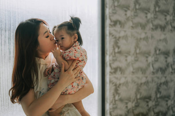китайский новый год китайская мать целует дочь дома утром - mother baby new kissing стоковые фото и изображения