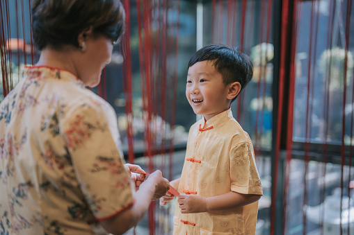 Chinese New Year Grandmother giving angpao red packet to grandchild at home