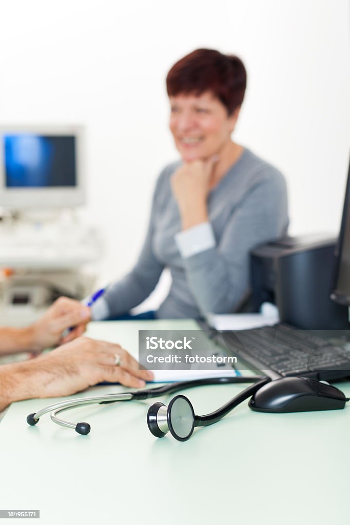 Doctor and patient talking about ultrasound medical exam Female patient sitting in doctor's office preparing for ultrasound medical exam. Ultrasound machine is in the background, focus is on the stethoscope in the foreground. 30-39 Years Stock Photo