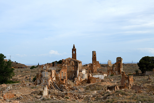The photo shows the remains of the Church of San Martin de Tours at Belchite are in the province of Zaragoza, Spain. It is surrounded with rubble and destroyed houses of the town. To the left a green tree shows nature survives.\n\nBetween August 24 and September 7, 1937, during the Spanish Civil War, loyalist Spanish Republican forces fought General Franco's rebel forces in the Battle of Belchite in and around the town. In the battle the church was destroyed. Franco ordered that the ruins be left untouched as a \