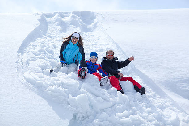 istock happy family sliding down snowy hill 184955487