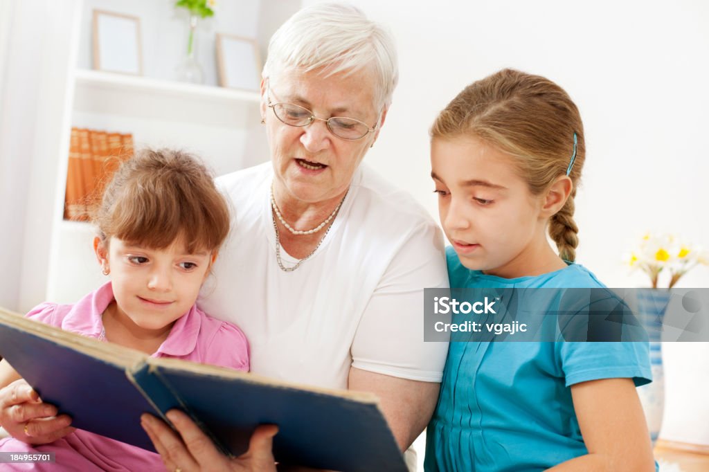 Nonna leggendo il libro per i suoi nipoti - Foto stock royalty-free di 4-5 anni
