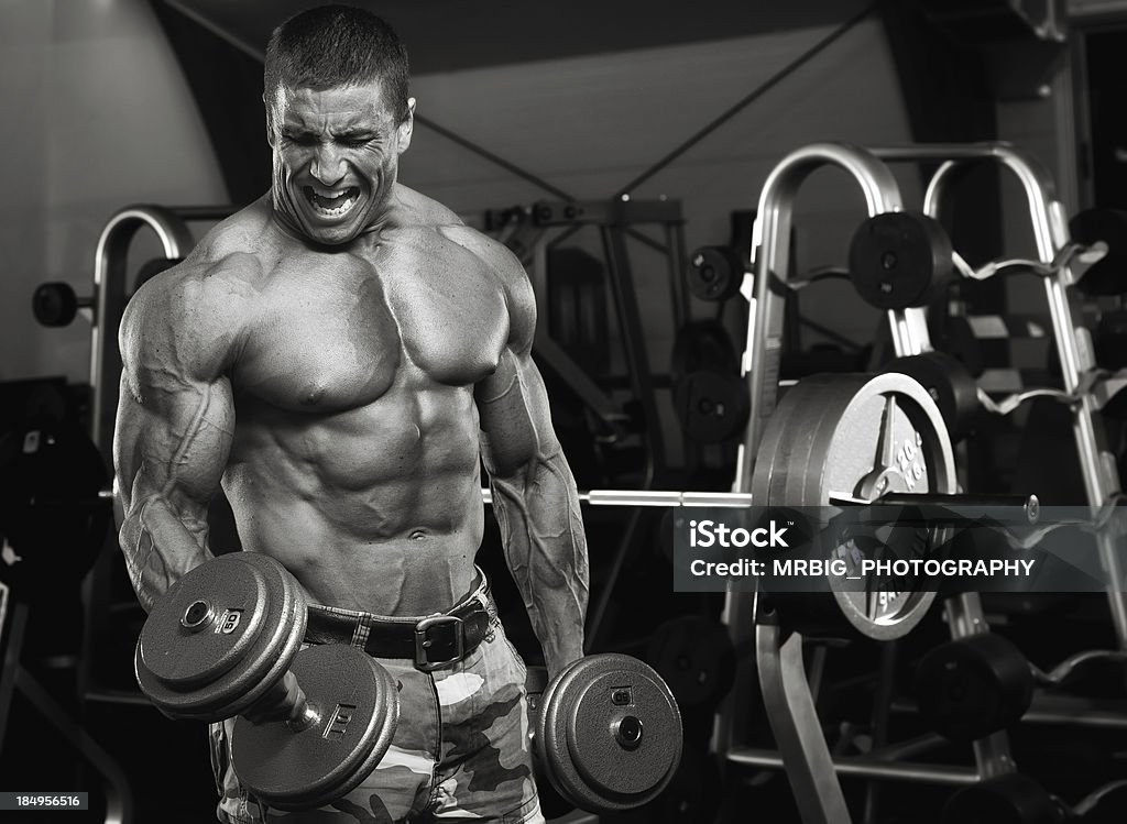 Intensity Muscular Men Exercise in The gym with dumbbells. Black And White Image. Abdominal Muscle Stock Photo