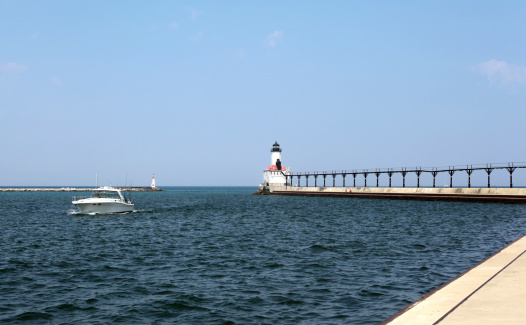 Speedboat entering Michigan City harbor past lighthouse.  Copy space.  Horizontal.