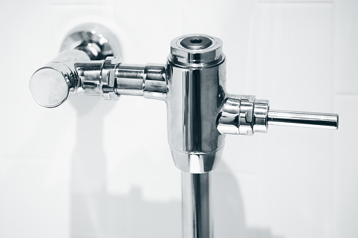 Closeup Exposed Manual Water Closet Flushometer. Flush Valve for Toilets Flushing System Dual Flow Type.
