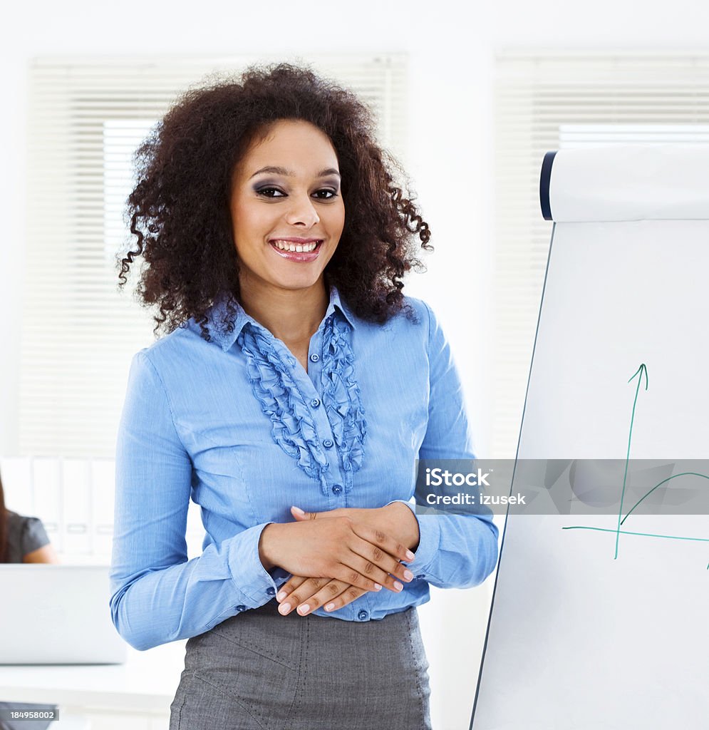 Business training Focus on the young businesswoman giving presentation on the flip chart and smiling at camera. 25-29 Years Stock Photo