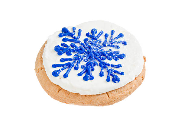 Snowflake Sugar Cookie A High angle close up of a sugar cookie with white frosting with  a blue snowflake pattern on it. Isolated on white. white sugar cookie stock pictures, royalty-free photos & images