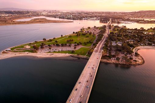 Experience the breathtaking beauty of Mission Bay and Pacific Beach in San Diego, California. This aerial view captures the picturesque drive bridge, the lush green bay, the sandy shores of the Pacific, and the expansive sky above the bay