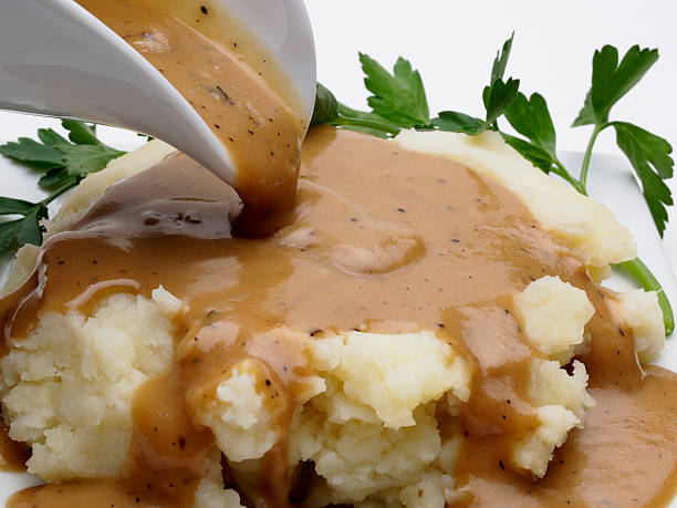 Mashed Potatoes and Gravy Close up of gravy boat pouring over mashed potatoes gravy photos stock pictures, royalty-free photos & images
