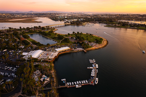Experience the enchanting views from Vacation Isle in Mission Bay, San Diego, as the sun dips below the horizon, casting a warm glow over the bay. This aerial masterpiece captures the serene beauty of the sunset, highlighting the picturesque dock for boats and the tranquil waters adorned with scattered boats