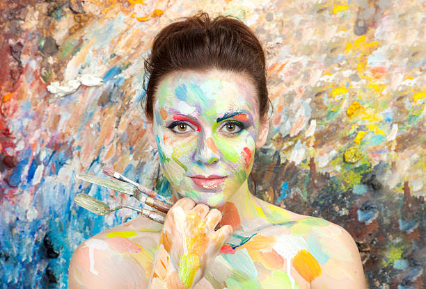 A young beautiful woman wearing red dress on black background. pretty young woman holding a palette and looking through it's hole.