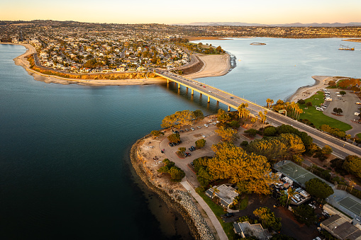 Experience the breathtaking beauty of Mission Bay and Pacific Beach in San Diego, California. This aerial view captures the picturesque drive bridge, the lush green bay, the sandy shores of the Pacific, and the expansive sky above the bay