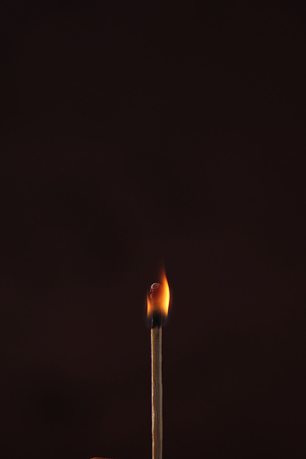 one lit match on a dark background