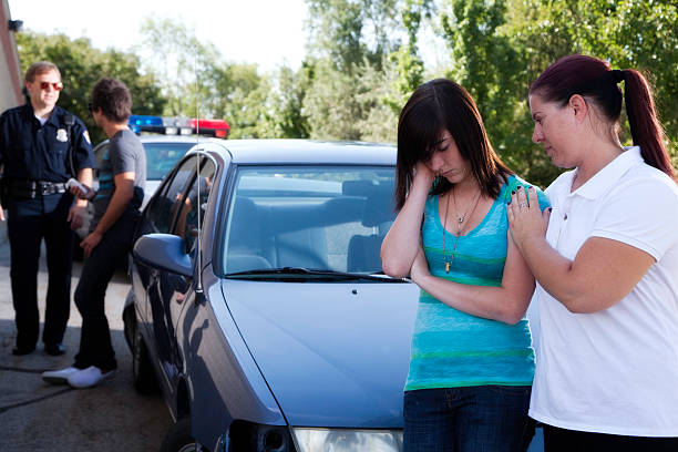 Mother Comforts Daughter After Accident or Police Stop "A mother comforts her daughter after a minor accident or traffic stop, which the police officer talks to her boyfriend in the background.Shot with Canon 5D Mark II, image processed in Pro Photo from a 16 bit RAW file.  Slight color saturation added.  Shot at Utahlypse 2011." child arrest stock pictures, royalty-free photos & images