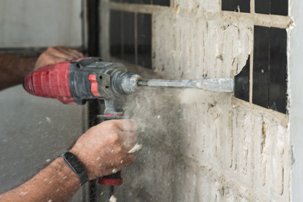 istock Builder with a puncher dismantles old tiles from a concrete wall 1849602657