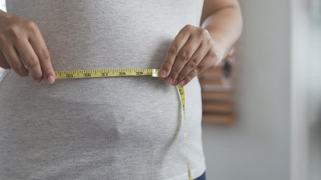 Woman measuring her waist with measure tape
