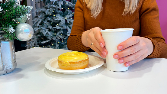 Woman with Christmas present, coffee cup and donut sitting at table in cafe