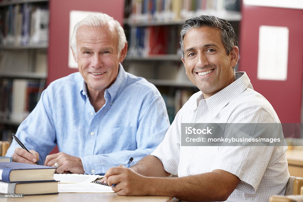 Mature students working in library Mature students working in library smiling at camera Learning Stock Photo