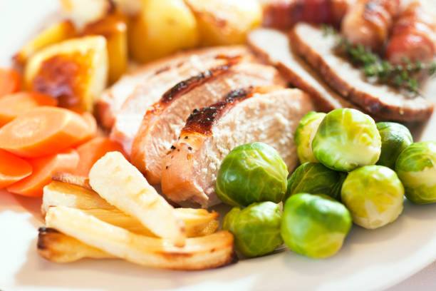 Christmas turkey dinner with Brussels sprouts, parsnips, carrots, roast potatoes, stuffing and pigs in blankets (sausages wrapped in bacon).