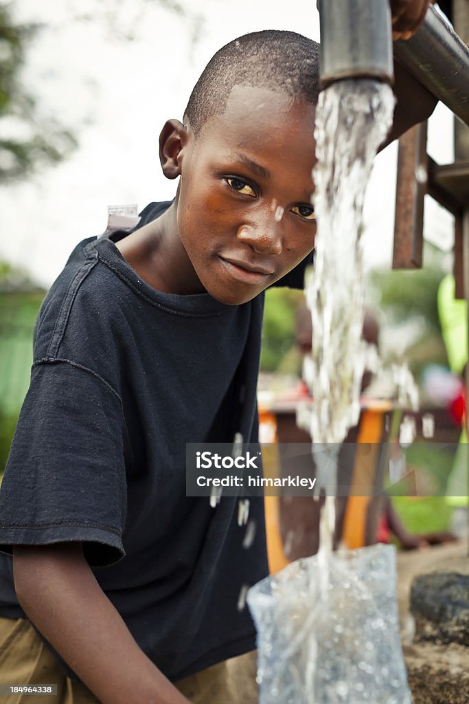 Ragazzo africano con pompa dell'acqua - Foto stock royalty-free di Acqua potabile