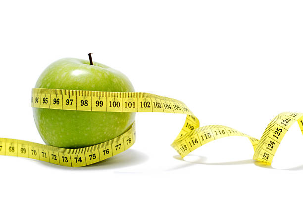 close-up di una mela con nastro di misurazione - weights dieting apple healthy eating foto e immagini stock