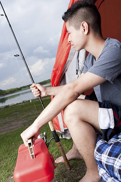 Teenager sitting in his tent getting ready to go fishing