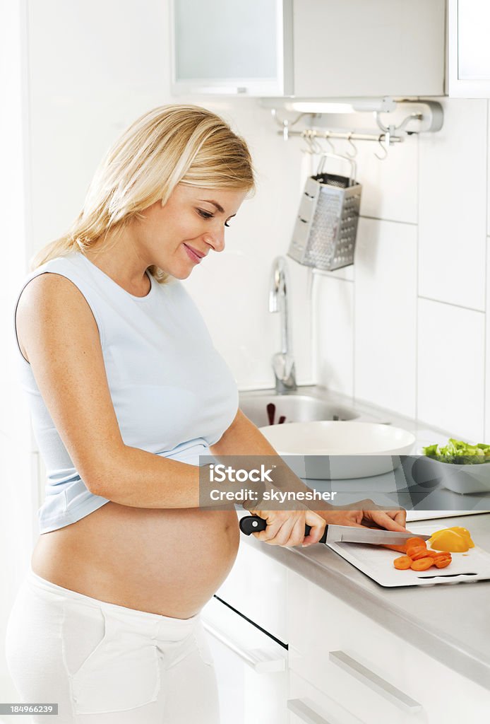 Mujer embarazada picar zanahorias - Foto de stock de Abdomen libre de derechos