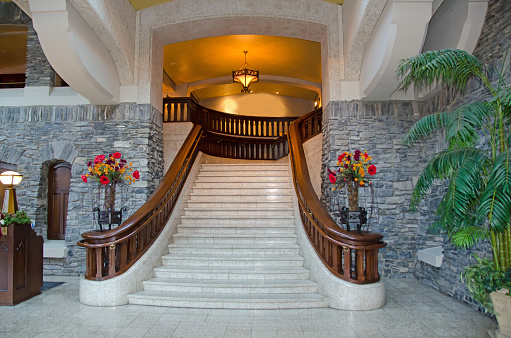 An impressive stairway made of marble with arches and a chandelier at the top. The stairs are in the Banff Springs Hotel lobby in Banff, Alberta.