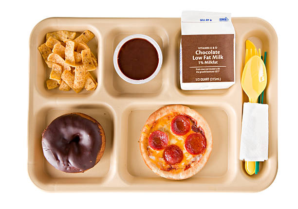 Unhealthy School Lunch "An overhead close up view of a tray containing an unhealthy school lunch consisting of a personal size pepperoni pizza, salty chips, a chocolate doughnut, chocolate pudding and chocolate flavored milk. Isolated on white." school lunch stock pictures, royalty-free photos & images